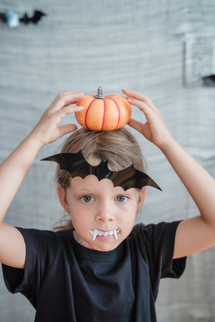 little girl with halloween decorations and fake vampire teeth